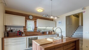 A modern kitchen with wooden cabinets, a central island, and a built-in oven. - VILLA MARCO In front of sea (Okrug Gornji)
