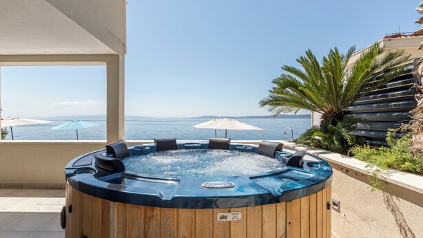 A hot tub with a view of the sea, surrounded by outdoor furniture and umbrellas. - VILLA MARCO In front of sea (Okrug Gornji)