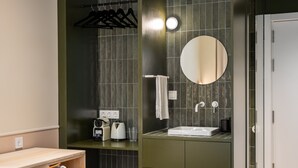 A modern bathroom with a sink, mirror, towel rack, and a small seating area with a chair.