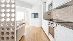 Une cuisine moderne avec des armoires blanches, un mur de fond en briques et des appareils électroménagers en acier inoxydable.