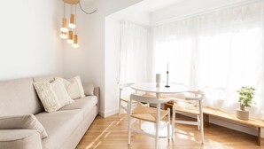 Un salon moderne avec un canapé beige, une table ronde blanche et un banc.