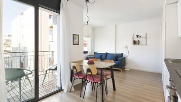 Una sala moderna con comedor, un sofá y un balcón con vistas a edificios.