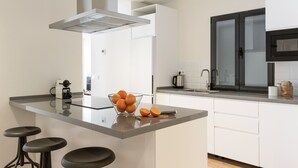Une cuisine moderne dotée d’un îlot central, de tabourets de bar, d’une bouilloire et d’un four à micro-ondes.
