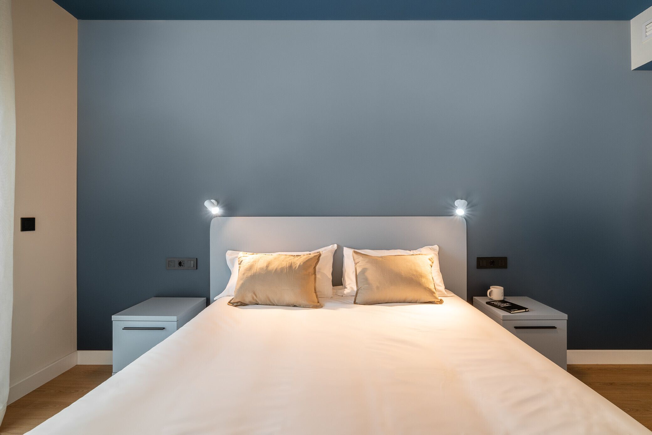 A bedroom with a bed, two bedside tables, and a nightstand.