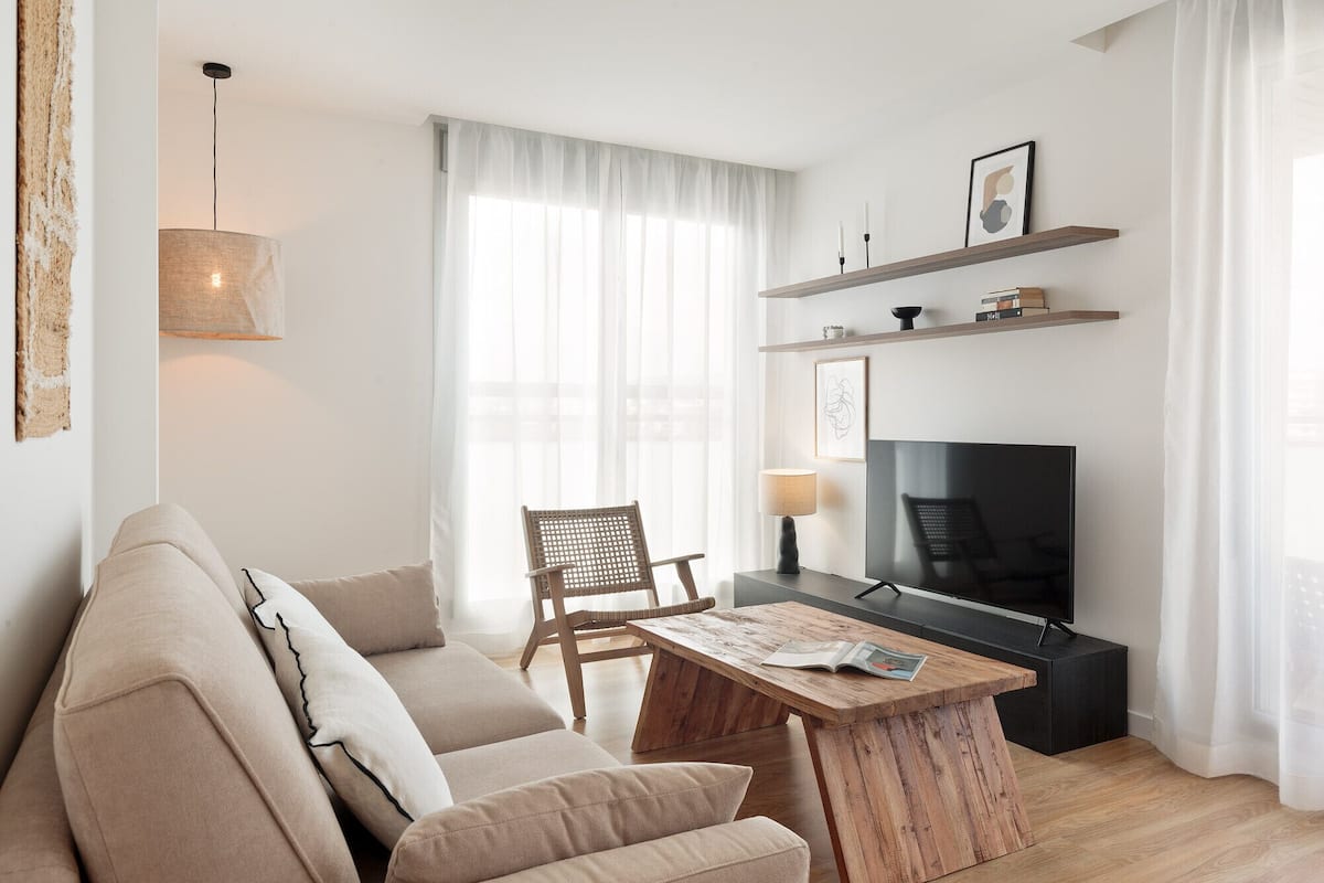 Un salon moderne avec un canapé, une table basse en bois, un téléviseur et une bibliothèque.
