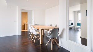 A modern dining area with a wooden table and chairs, a large mirror, and a view into another room. - Port Forum Apartments By Olala Homes (Sant Adria de Besos)