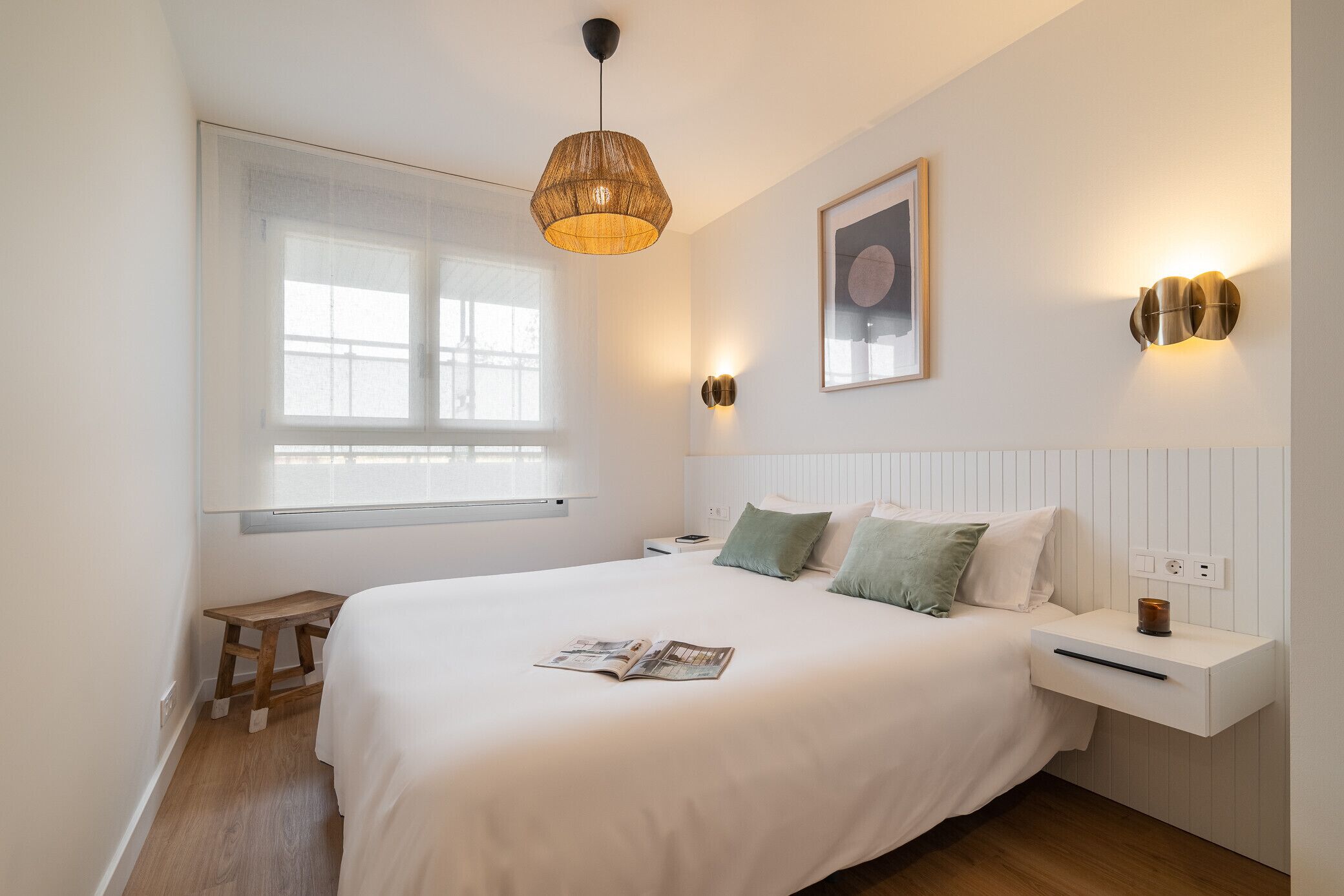 A bedroom with a large bed, bedside table, lamp, and a window.