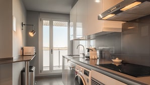 A modern kitchen with a built-in washing machine, a stovetop, and a view of the outdoors. - Port Forum Apartments By Olala Homes (Sant Adria de Besos)