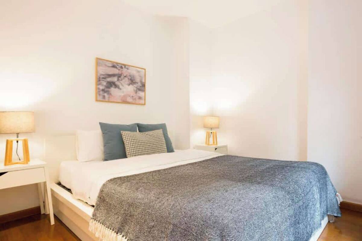 A neatly arranged bedroom with a bed, two bedside tables, and a wall-mounted lamp.