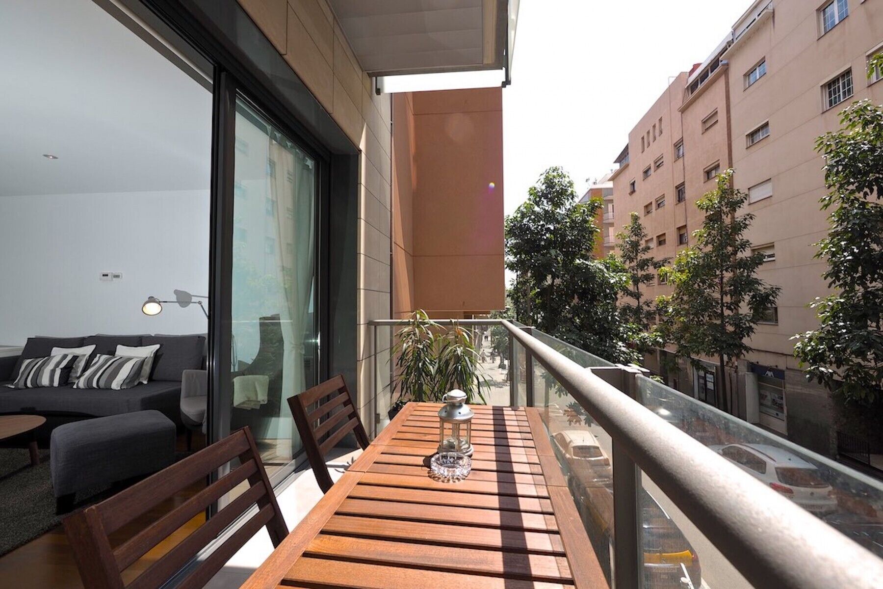 A balcony with a wooden table, chairs, and a potted plant.