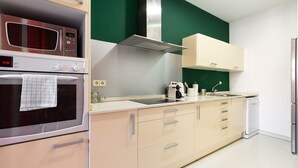 Une cuisine moderne équipée d’un four encastré, d’un four à micro-ondes et d’un grille-pain. On y trouve un évier avec un robinet, ainsi que des placards dotés de poignées.