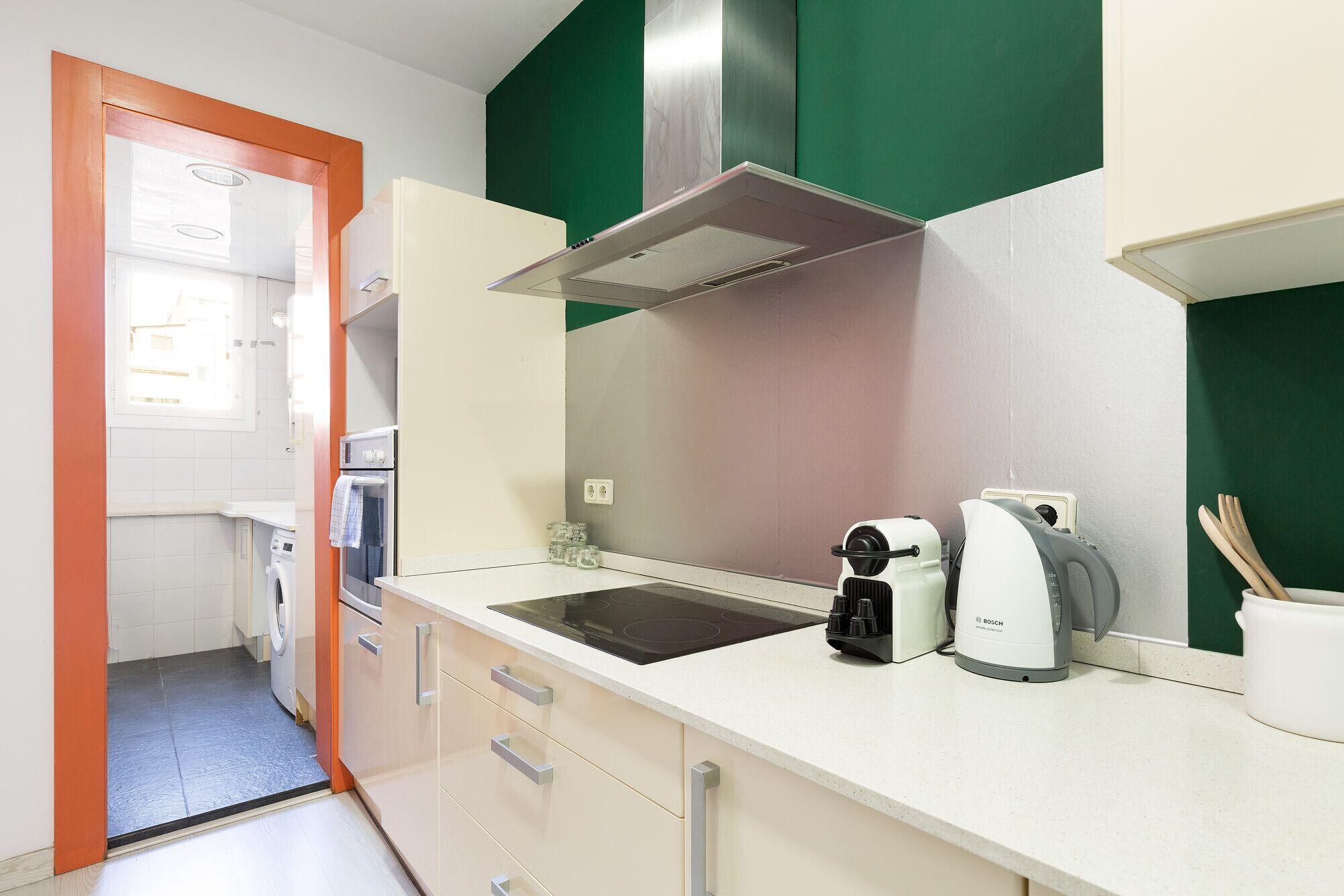 A modern kitchen with a built-in oven, a Bosch coffee maker, and a kettle on the countertop.