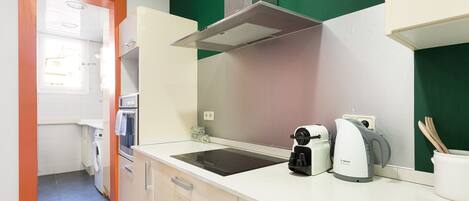 A modern kitchen with a built-in oven, a Bosch coffee maker, and a kettle on the countertop.
