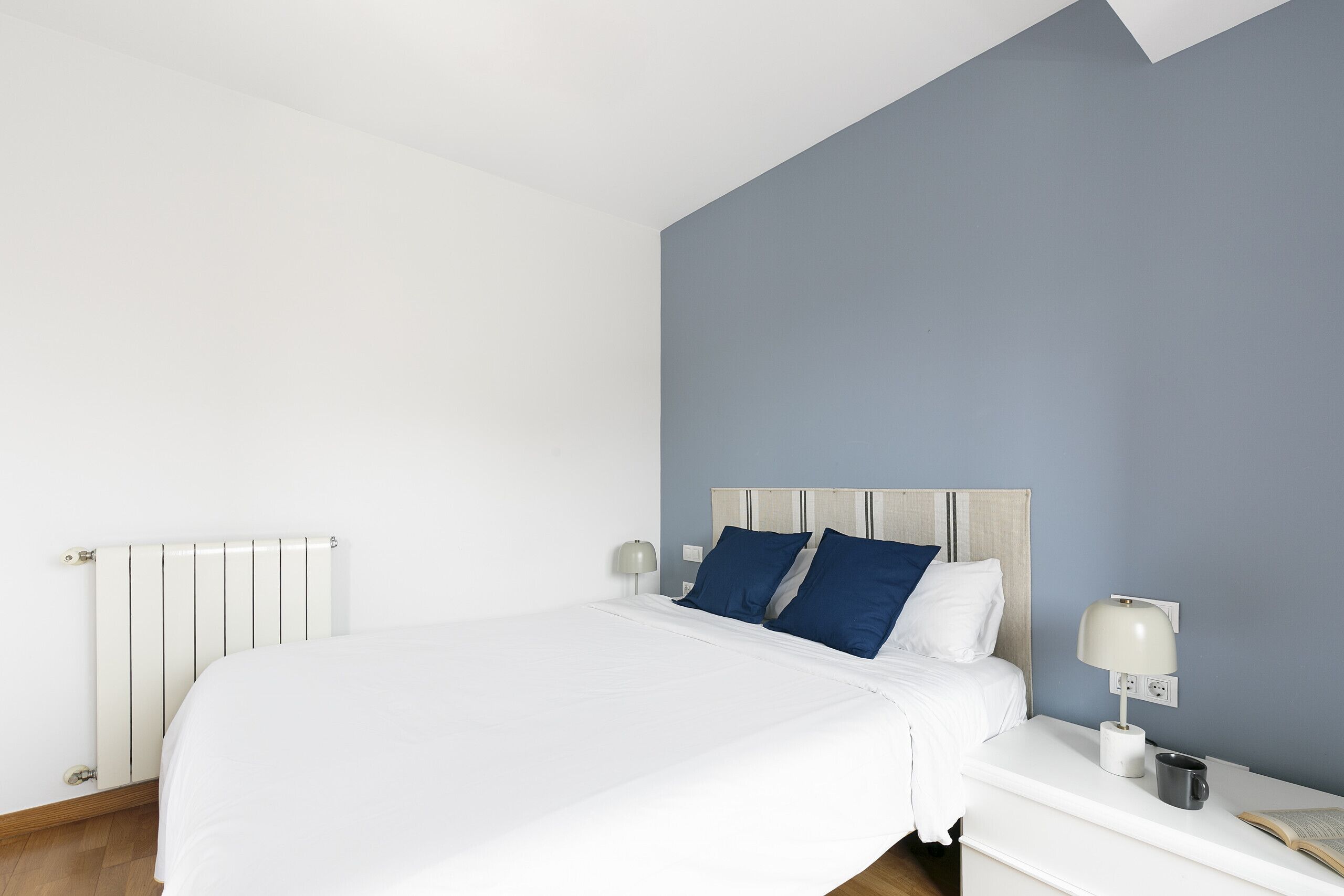 Une chambre moderne avec un grand lit, une table de chevet avec une lampe et un radiateur.