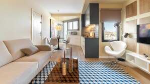 A modern living room with a sofa, a coffee table with candles, a patterned rug, and a city view through the window.