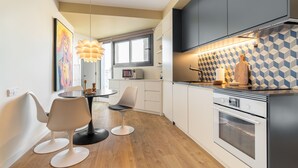 A modern kitchen with white cabinets, a black stove, and a geometric backsplash.
