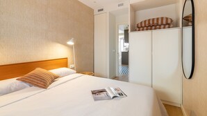 A hotel room with a bed, a wardrobe, a mirror, and a magazine on the bed.