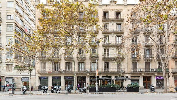 A multi-story building with balconies, storefronts, and outdoor seating areas. - Señor Urgell Apartment By Olala Homes (Barcelona)