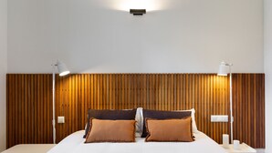 A modern bedroom with a wooden headboard, two bedside lamps, and a white bedspread. - Señor Urgell Apartment By Olala Homes (Barcelona)