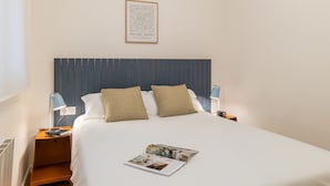 A neatly made bed with two pillows, a framed picture above it, and a magazine on the bed. - Rafael Apartment by Olala Homes (L'Hospitalet de Llobregat)