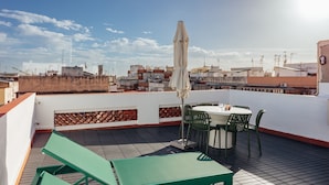 Una terraza en la azotea con una mesa, sillas, una sombrilla y vistas de la ciudad.