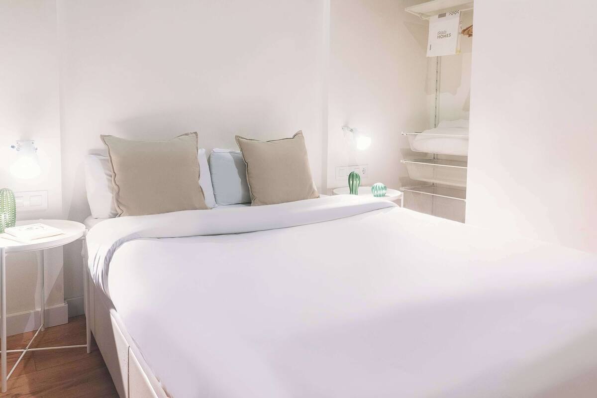 Un dormitorio ordenado con una cama grande, dos mesitas de noche y una mesilla.