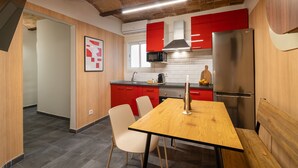 Een moderne keuken met rode kastjes, een roestvrijstalen koelkast en een houten eettafel.