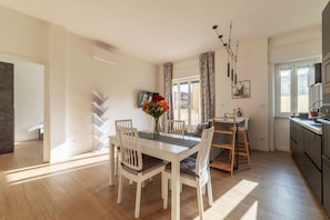 Une cuisine moderne avec un coin repas, un plancher en bois et une vue sur lâextĂ©rieur.