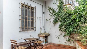 A patio with a table and chairs, a window with a metal grille, and a wall with climbing plants. - GuestHost - Comfortable apartment of approximately 50 square meters, able to accommodate up to 4 people, located on the ground floor of an ancient building, but in good condition. The apartment is located in the Porta Romana-Boboli district (Traffic-Rest (Firenze)