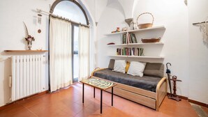 A cozy living room with a sofa, a small table, a radiator, and a bookshelf. - GuestHost - Comfortable apartment of approximately 50 square meters, able to accommodate up to 4 people, located on the ground floor of an ancient building, but in good condition. The apartment is located in the Porta Romana-Boboli district (Traffic-Rest (Firenze)