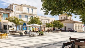 Une place publique dotée d’un espace extérieur aménagé avec des sièges, d’une fontaine et d’un bâtiment historique surmonté d’un clocher.