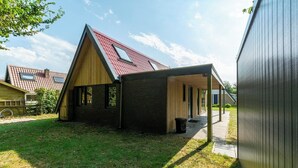 A modern house with a sloped roof, a covered porch, and a brick exterior. - Holiday Home Groote Keeten near Beaches (Groote Keeten)