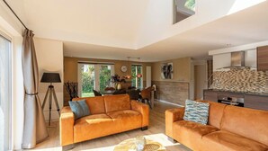 A spacious living area with two sofas, a dining table, and a kitchen in the background. - Holiday Home Groote Keeten near Beaches (Groote Keeten)