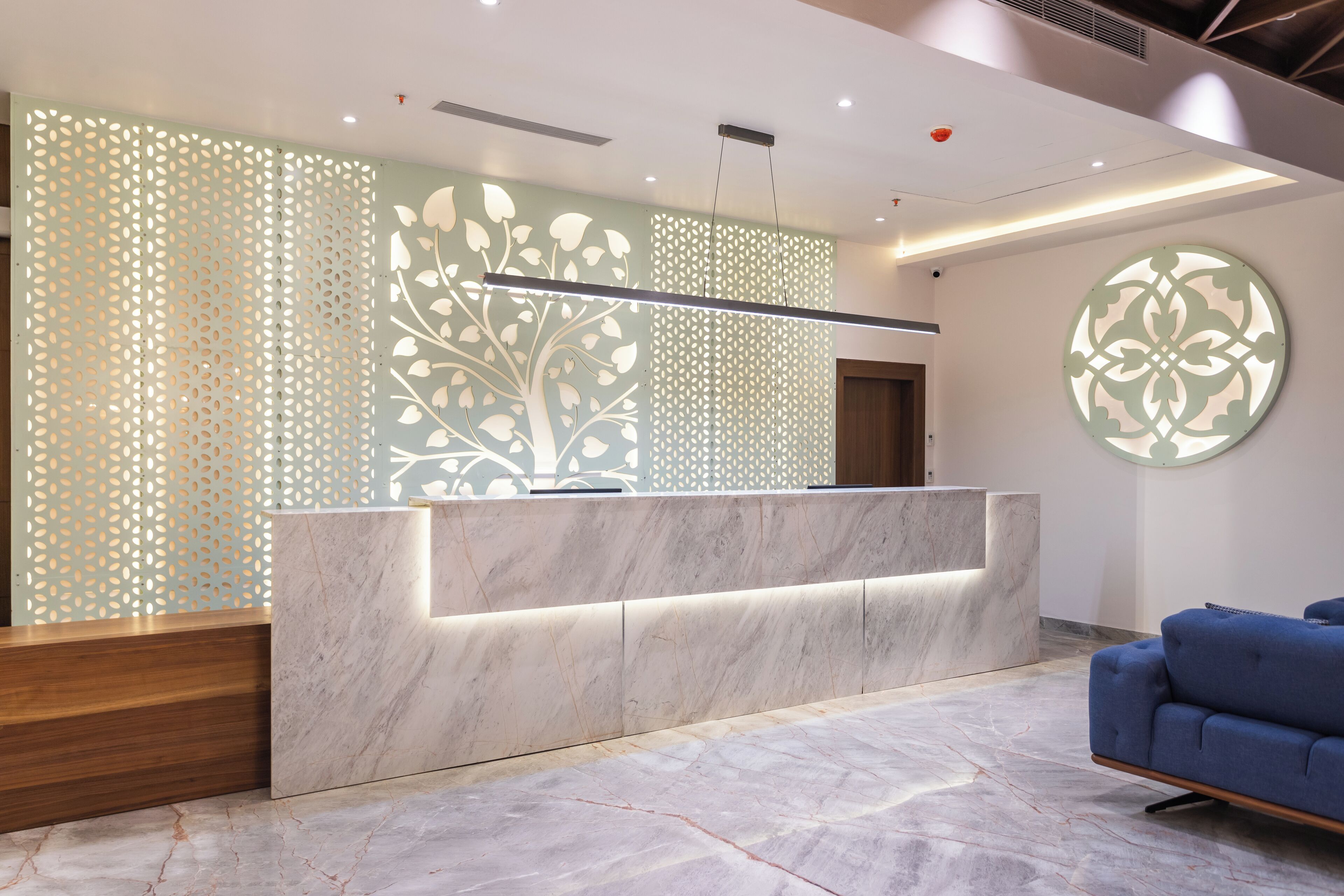 A reception area with a marble counter, a blue sofa, and decorative wall panels.
