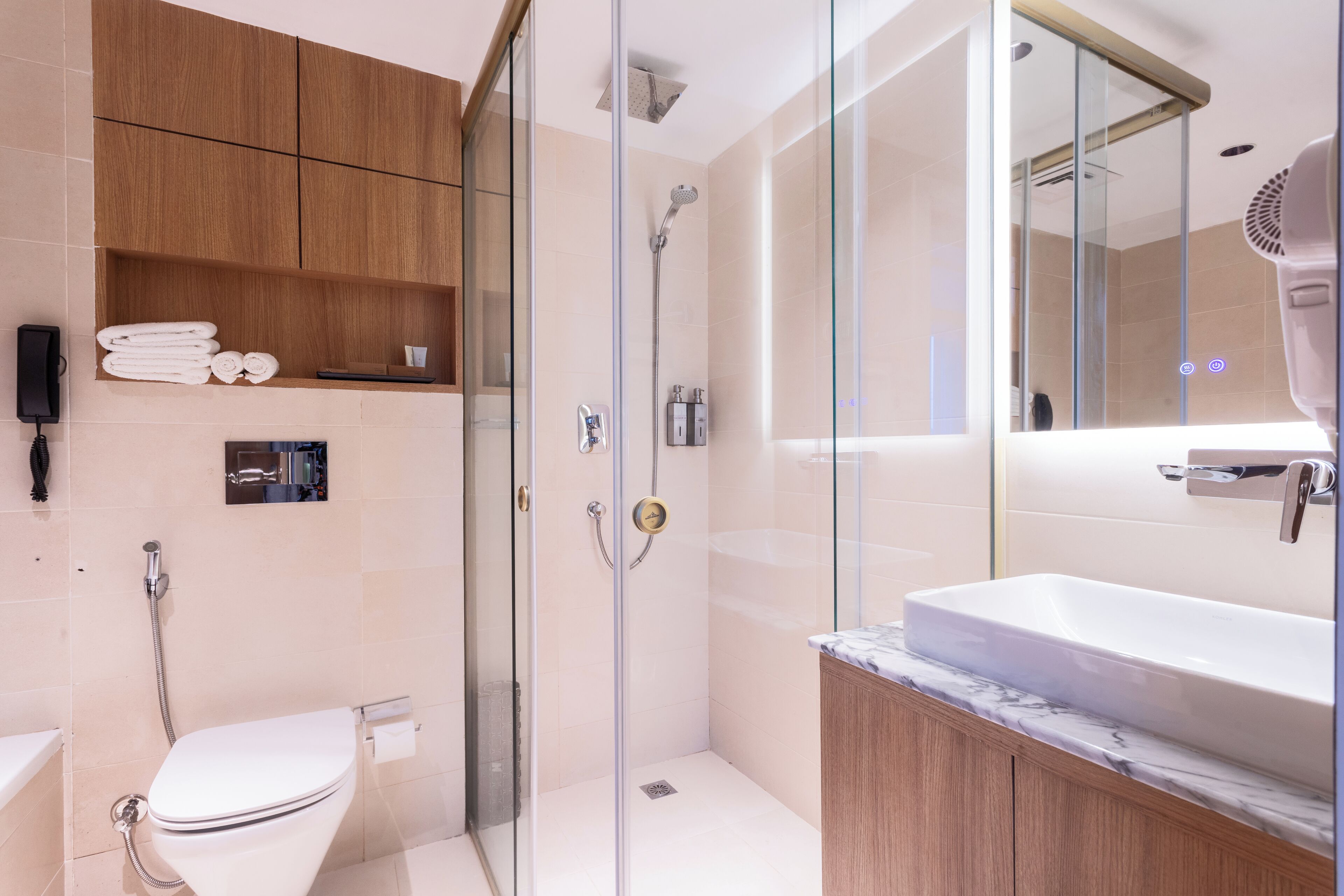 A modern bathroom with a glass-enclosed shower, a white sink, and wooden cabinets.