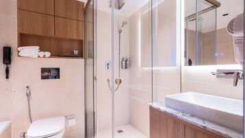 A modern bathroom with a glass-enclosed shower, a white sink, and wooden cabinets.