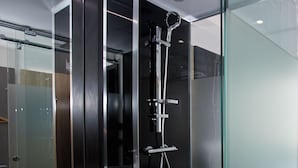 A modern bathroom with a glass shower enclosure, a white sink, and a dark mirror. - The Z Hotel Tottenham Court Road (London)