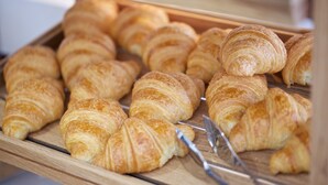 A tray of assorted pastries, including croissants and other baked goods, arranged on a wooden board. - The Z Hotel Tottenham Court Road (London)