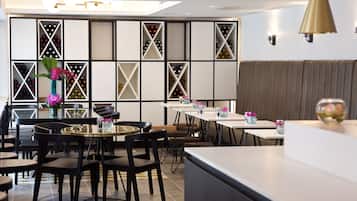 A modern restaurant interior with black and white geometric wall panels, round tables, and black chairs.
