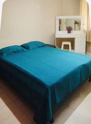 Een slaapkamer met een bed, een wit bureau en een stoel.