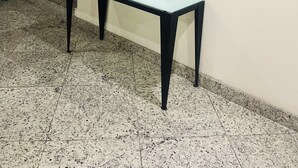 Eine Lobby mit Marmorboden, einem Tisch mit Glasplatte und zwei Wandspiegeln.