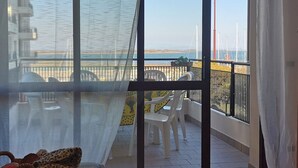 A balcony with a view of the sea, a bed, and a chair. - Lagoon charm apartment by Beahost Rentals (Lignano Sabbiadoro)