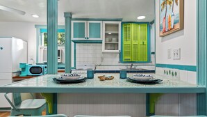 Une cuisine avec des meubles de couleur turquoise, un îlot central doté de chaises et un four à micro-ondes.
