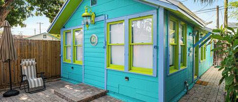 A turquoise house with green window frames and a small porch area.