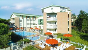 Een hotel met een groot zwembad, diverse ligbedden en parasols.