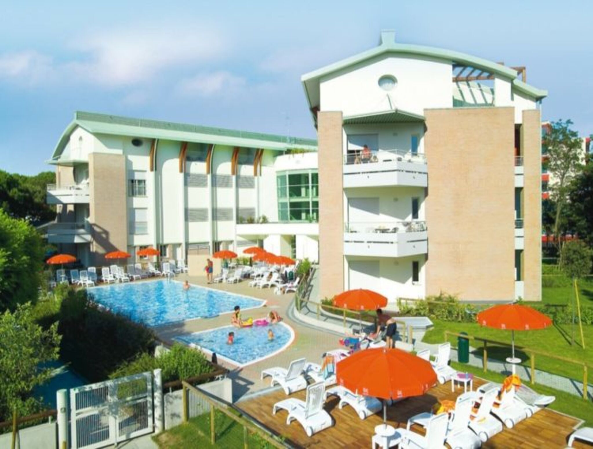 Ein Hotel mit Schwimmbad, Liegestühlen und Sonnenschirmen.