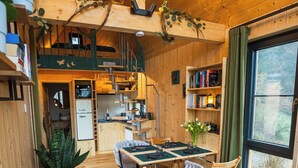 A cozy cabin interior with a wooden dining area, a sofa, and a kitchen in the background. - Taunus Tinyhouse (Weilrod)