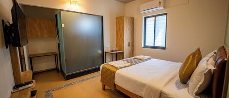 A hotel room with a bed, a television, a ceiling fan, a window, and an air conditioning unit.