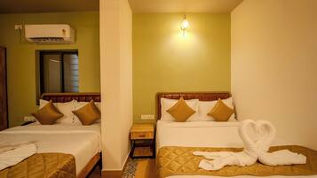 A hotel room with two beds, a nightstand, an air conditioner, and a wall-mounted light fixture.