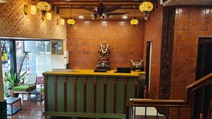 A reception area with a wooden counter, a statue, and a staircase. - Atithyaa (Bengaluru)